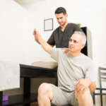 Physiotherapist helping elderly patient with hand exercises at home in Dubai – Bridges Speech Center.
